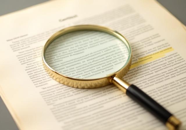 Magnifying glass over a complex legal document with highlighted text